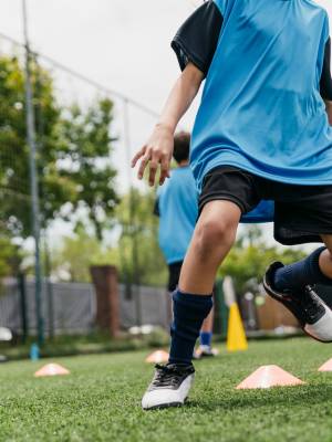 Low angle view of girls and boys practicing soccer drills. Determined football players are preparing for match with friends in background. They are in sports uniform.